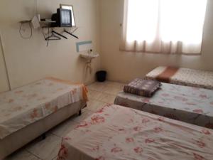 Habitación con 3 camas y TV. en Hotel Santa Marta, en Ribeirão Preto