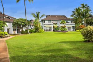 a large yard with a large house with palm trees at Aston At Poipu Kai in Koloa