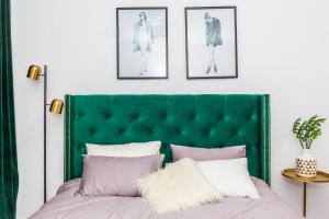 un cabecero verde en un dormitorio con almohadas rosas y blancas en Qingdao Shinan·Qingdao Landing Stage· Locals Apartment 00133930 en Qingdao