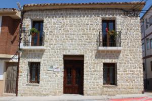 un edificio de ladrillo con tres ventanas con flores. en Casa Rural Los Montones, en Carcelén