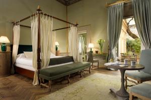 a bedroom with a canopy bed and a table and chairs at Al Palazzo del Marchese di Camugliano Residenza d'Epoca in Florence