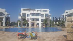 a group of people sitting in lawn chairs by a swimming pool at Appart Aga Hivernage in Agadir