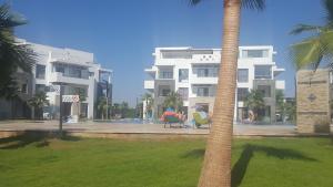 a large white building with a palm tree in front of it at Appart Aga Hivernage in Agadir