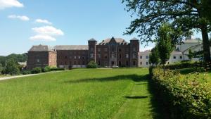 a large brick building with a large grass field at Le p'tit gîte d'Enhet in Ciney