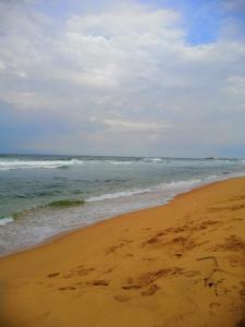 une plage de sable avec des vagues dans l'océan dans l'établissement Wick's Apartment, à Hikkaduwa