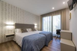 a hotel room with a large bed and a window at Hotel A Curuxa Wellness in Arzúa