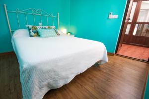 a blue bedroom with a large white bed with blue walls at Apartamento Ciudad Monumental in Cáceres