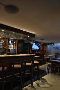 a bar with wooden chairs and tables and a television at Hotel Bonanza Inn in Guayaquil