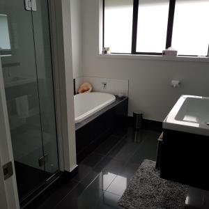 een badkamer met een bad en een wastafel bij Papamoa Retreat in Tauranga