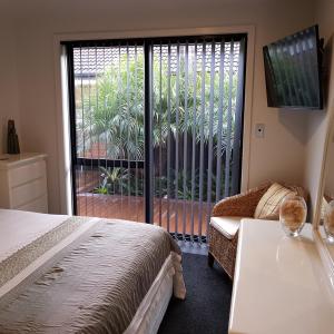 um quarto com uma cama e uma porta de vidro deslizante em Papamoa Retreat em Tauranga