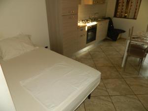 1 dormitorio con 1 cama blanca y cocina en Appartamento Mira, en Cislago