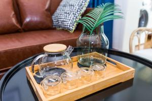 a tray with glasses and a vase on a table at Qingdao Shibei·Kaide Mall· Locals Apartment 00151110 in Qingdao