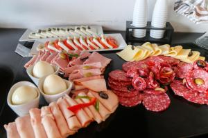 a table topped with different types of meats and cheese at Hotel Martín Gusinde in Puerto Natales