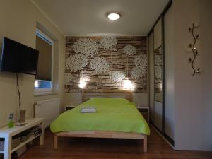 een slaapkamer met een groen bed en een bakstenen muur bij Sarni Stok in Bielsko-Biala