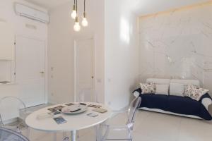 a white living room with a table and a bed at Relais Mareluna - Luxury Apartments in Salerno