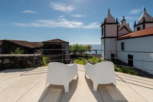 dwa białe krzesła siedzące na dachu domu w obiekcie T1 Casa das Pereiras w mieście Calheta de Nesquim