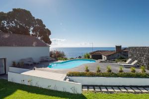 un patio trasero con piscina y océano en T2 Lux Casa das Pereiras en Calheta de Nesquim