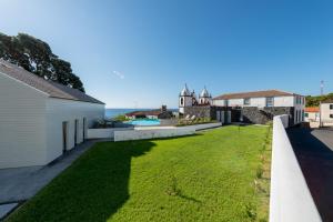 un patio abierto con césped junto a una casa en T2 Lux Casa das Pereiras en Calheta de Nesquim