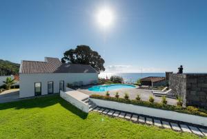 a house with a swimming pool next to the ocean at T2 Lux Casa das Pereiras in Calheta de Nesquim