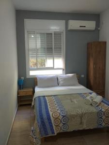 1 dormitorio con 1 cama grande y ventana en Ga'aton Motel, en Nahariyya