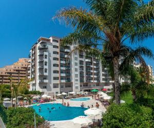 a resort with a large swimming pool and a palm tree at Flor Da Rocha in Portimão