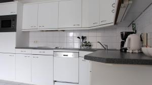 una cocina blanca con armarios blancos y fregadero en La vita e bella, en Ootmarsum