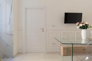 a white room with a glass table and a tv at Relais Mareluna - Luxury Apartments in Salerno