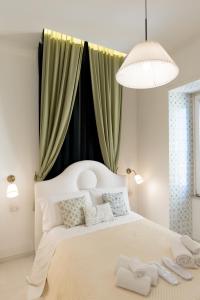 a bedroom with a large white bed with green curtains at Relais Mareluna - Luxury Apartments in Salerno