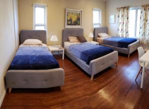 three beds in a room with wood floors at MyStayLA in Los Angeles