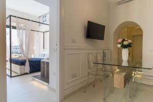 a dining room with a glass table and a tv at Relais Mareluna - Luxury Apartments in Salerno