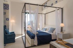a bedroom with a canopy bed and a chair at Relais Mareluna - Luxury Apartments in Salerno
