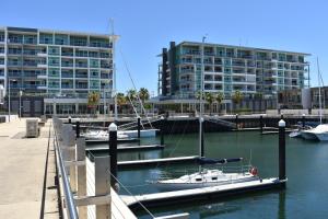 a group of boats docked in a marina with a building at Breakwater Apartment in Port Adelaide