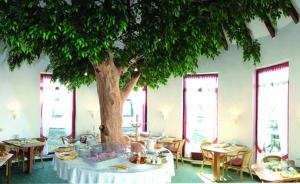 a table with a tree in a room with tables at Dillinger Hof in Dillingen an der Donau