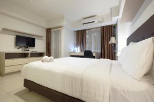 a hotel room with a large white bed and a television at Best Price Spacious Studio Apartment at H Residence near MT Haryono By Travelio in Jakarta