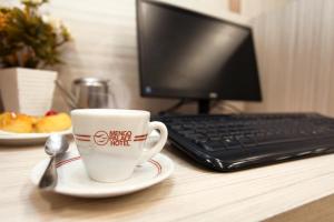 a coffee cup sitting on a desk with a computer at Mengo Palace Hotel in Rio de Janeiro
