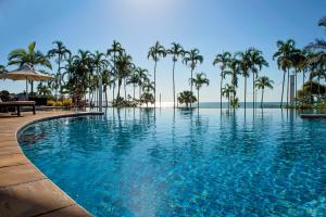 a swimming pool with palm trees and palm trees at Mindil Beach Casino Resort in Darwin