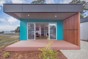 a small house with a blue wall and a deck at Tasman Holiday Parks - St Helens in St Helens