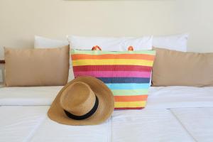 a straw hat sitting on a bed with pillows at Mengo Palace Hotel in Rio de Janeiro