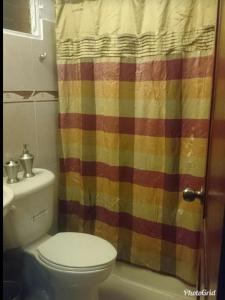 ein Bad mit einem WC und einem mehrfarbigen Duschvorhang in der Unterkunft PARADISE 3 Cerro Altos in Santiago de los Caballeros