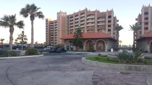 a parking lot with a building and palm trees at Sonoran Sun Resort in Puerto Peñasco