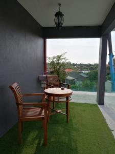 eine Terrasse mit 2 Stühlen, einem Tisch und einem Fenster in der Unterkunft Millenium maison home in Alor Setar