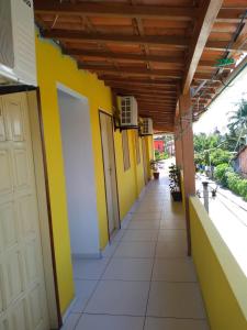 un couloir d'un bâtiment aux murs jaunes et blancs dans l'établissement Pousada Aritibe, à Île de Boipeba