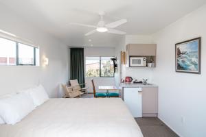 a bedroom with a white bed and a kitchen at Blue Marlin Apartments in Whitianga