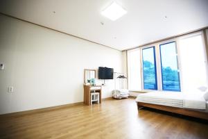 Habitación blanca con cama y ventana grande. en Flora hostelpension, en Yeosu