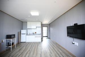 an empty room with a kitchen and a tv on a wall at Flora hostelpension in Yeosu