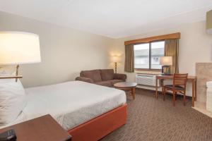 a hotel room with a bed and a desk at AmericInn by Wyndham Calumet in Calumet