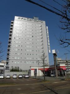 a large white building with cars parked in a parking lot at Hotel New Green Tsubame Sanjo in Sanjo