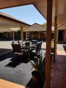 a patio with a table and chairs in a yard at Cotswold Motor Inn in Toowoomba