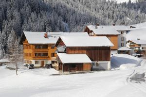 ein Blockhaus im Schnee mit schneebedeckten Dächern in der Unterkunft Landhaus Trista in Damüls