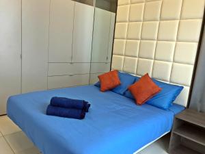 a bed with blue sheets and orange pillows on it at The Robertson KL in Kuala Lumpur